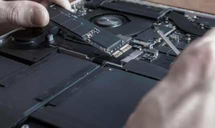 Technician handling an internal storage device from a disassembled laptop